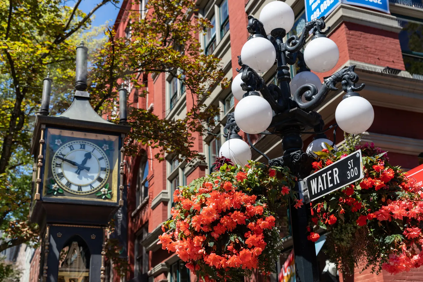 The Gastown steam clock on Water Street framed by flowers and old brick buildings