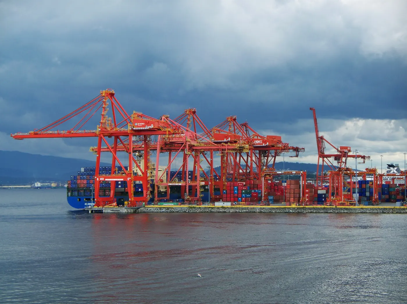 Red container cranes at the Port of Vancouver under heavy cloud